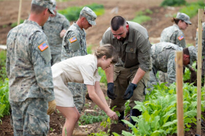 SHOCKING BASE VISIT: Taylor Swift & Travis Kelce Roll Up Sleeves to Plant Veggies with U.S. Soldiers – Then Drop a Jaw-Dropping 1-Ton Food Gift + Secret Surprise!